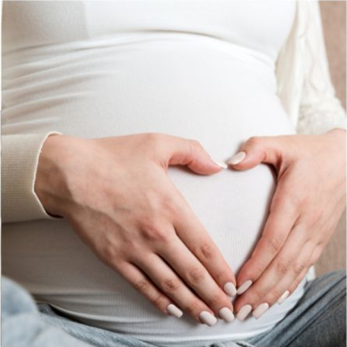 Vrouw die haar handen op haar zwangere buik houdt.
